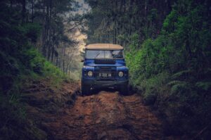 Véhicule tout-terrain traversant un chemin de terre accidenté à travers une forêt luxuriante à Parongpong, en Indonésie.