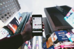 photo en plongée d'une personne tenant un smartphone allumé avec de grands immeubles en arrière-plan
